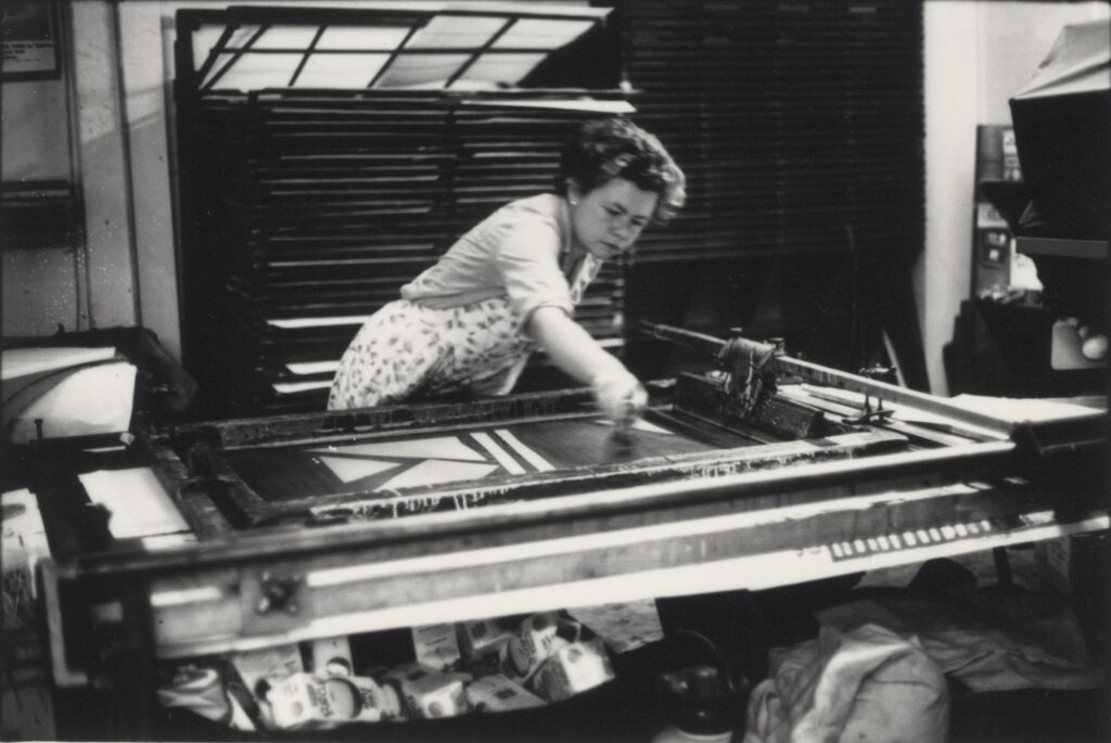 Black and white photograph of woman, Rebecca Wilson, using screen printing equipment