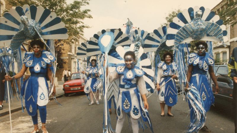 Five people dressed in blue and white peacock costumes posing in the middle of the street.