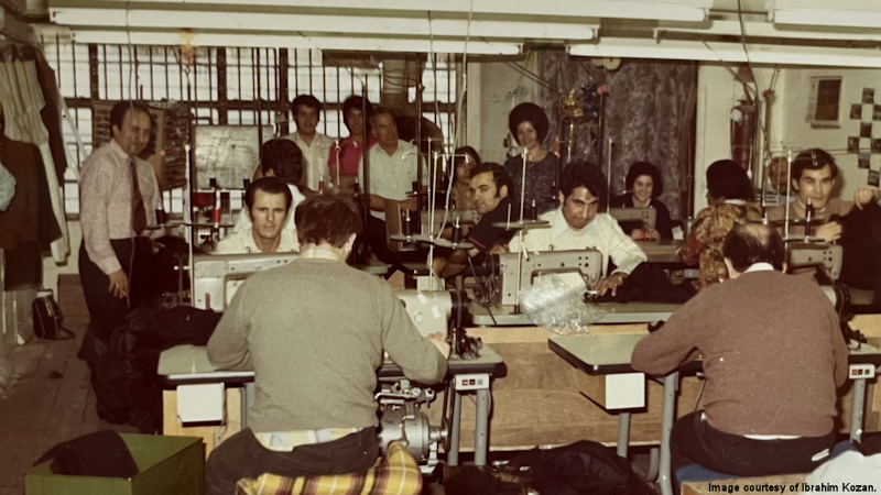 People sit at sewing machines in a garment factory