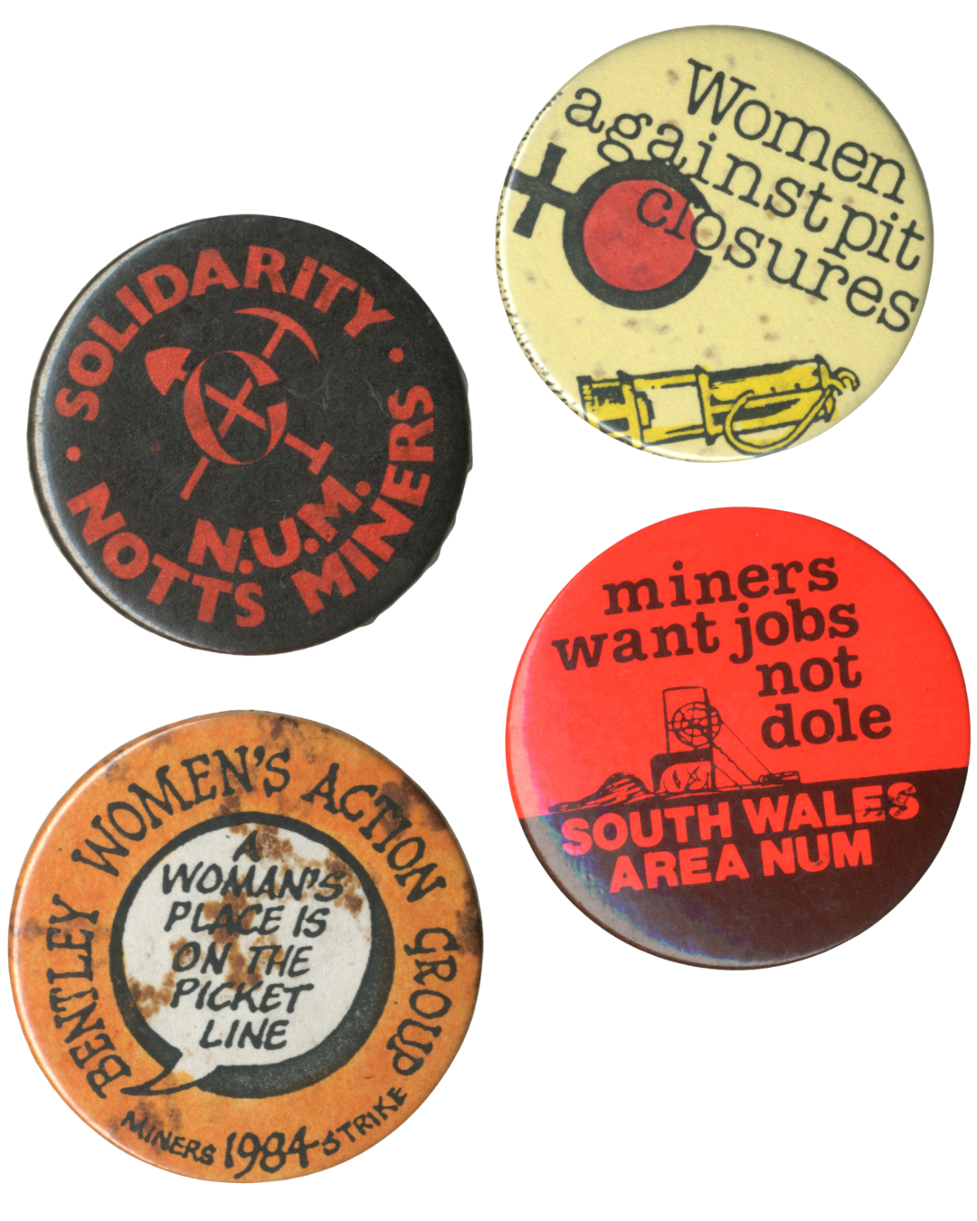 A colour photograph of 4 campaign badges, reading "Solidarity N.U.M Notts Miners", "women against pit closures", "Bentley Women's Action Group: A Woman's place is on the picket line", and "miners want jobs not dole South Wales Area NUM".