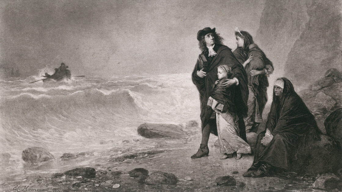 The image shows a family on the seashore: a couple with two children and an older woman seated on one of the rocks. The man looks back towards where they’ve come from and the woman towards the choppy waters from where a boat is heading towards them.
